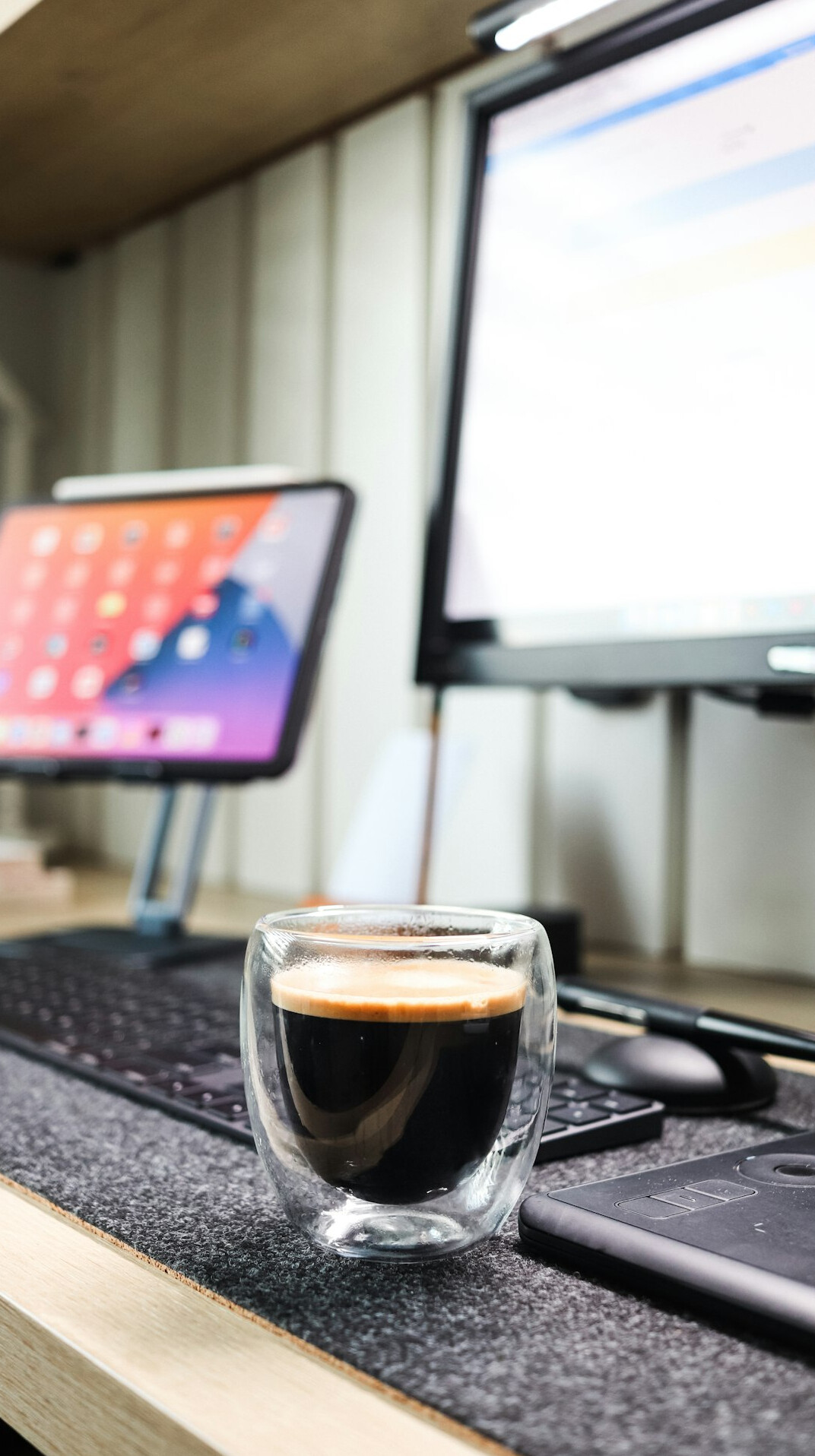 Desk with dual monitors showing code, a notebook and a cup of coffee